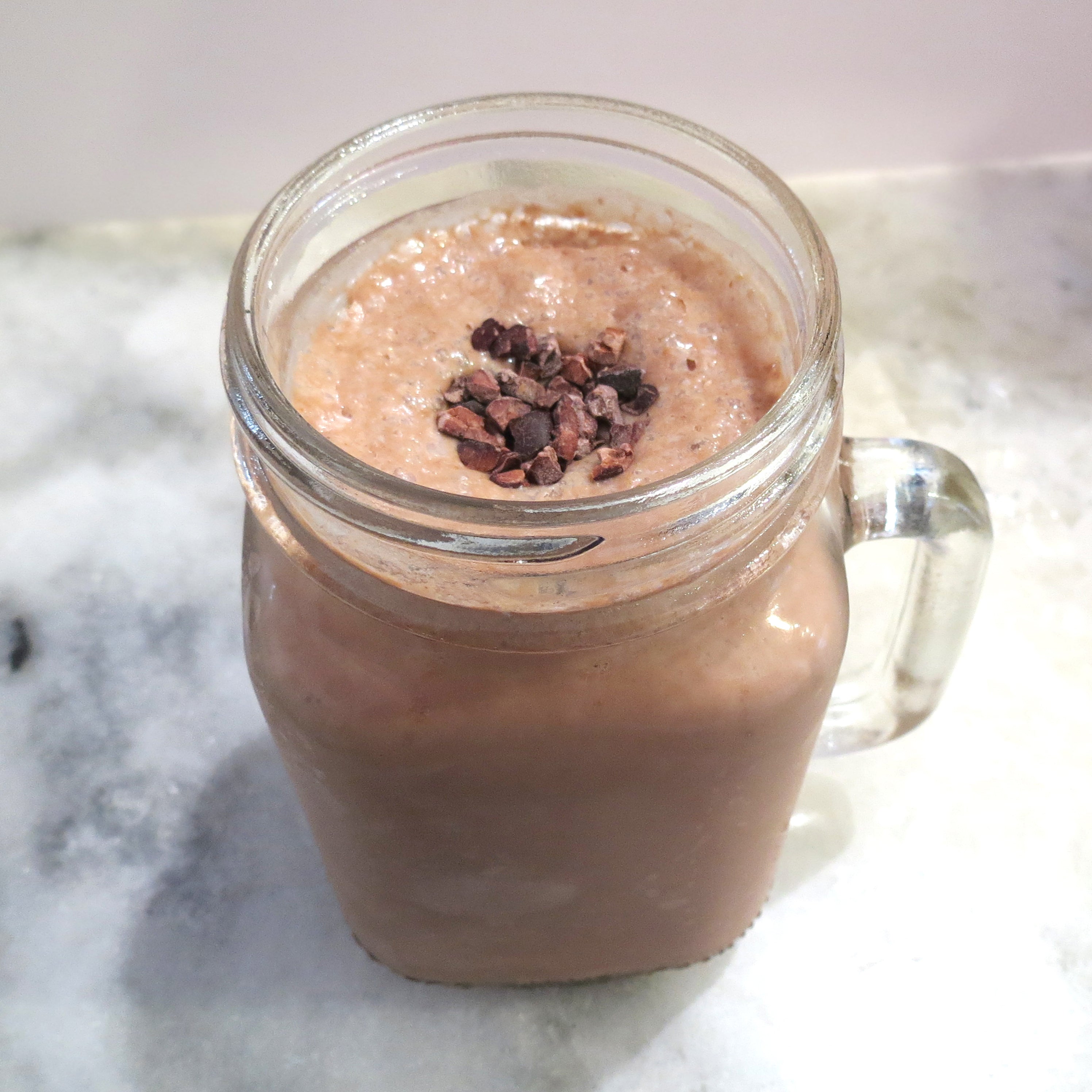 SpaJuiceBar's Banana Maca Mocha smoothie is made with bananas, homemade almond milk, organic raw cacao, vanilla, organic maca, and honey. Organic cacao nibs garnish the top of the smoothie. 16oz serving